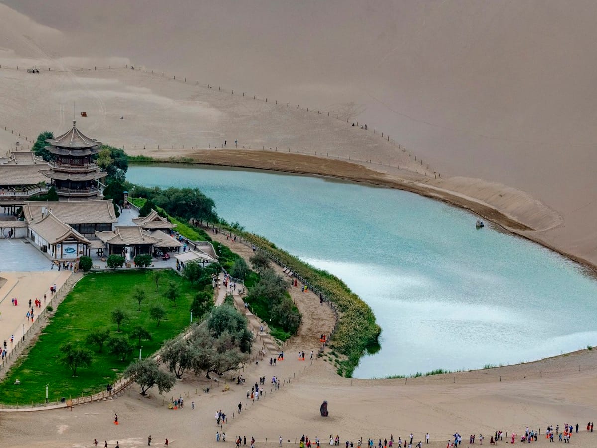 Aerial view of the Crescent Lake oasis with traditional pagodas surrounded by Mingsha sand dunes, Dunhuang, Gansu