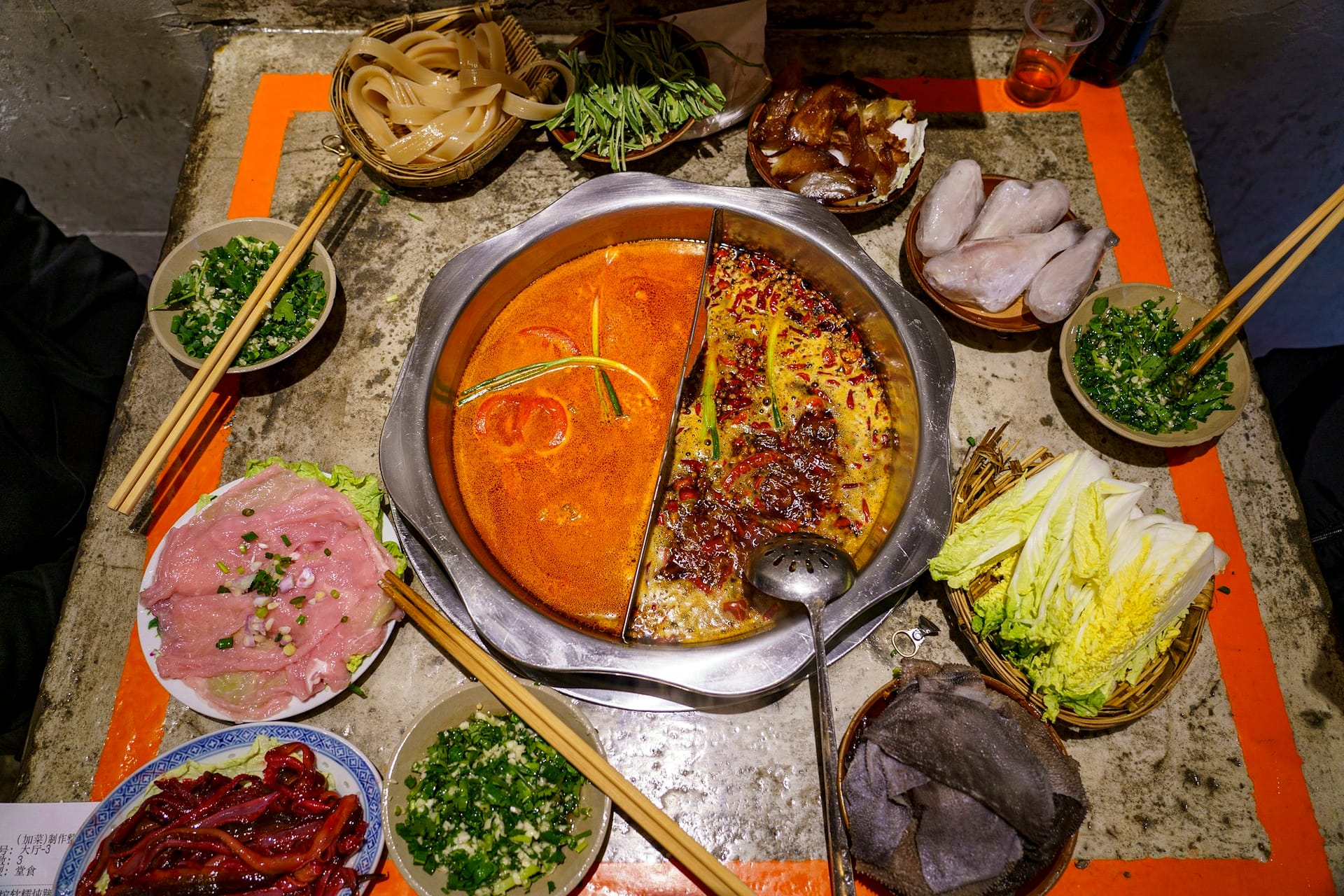 A bubbling Chongqing málà hotpot surrounded by dishes ready to cook